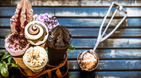 Assortiment de glaces artisanales gourmandes aux parfums variés présentées dans des cornets sur un support en bois